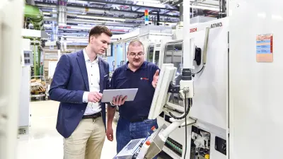 Bernhard Kohl zeigt Fabian Bucksch einen Fehler auf dem Monitor der Schleifmaschine.