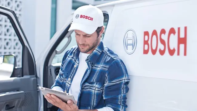 Servicetechniker von Bosch steht vor Bosch-PKW